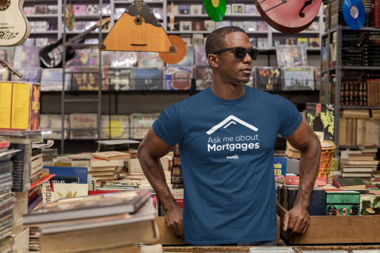 Blue T-shirt mockup with Ask me about Mortgages branding on a model in a record shop.